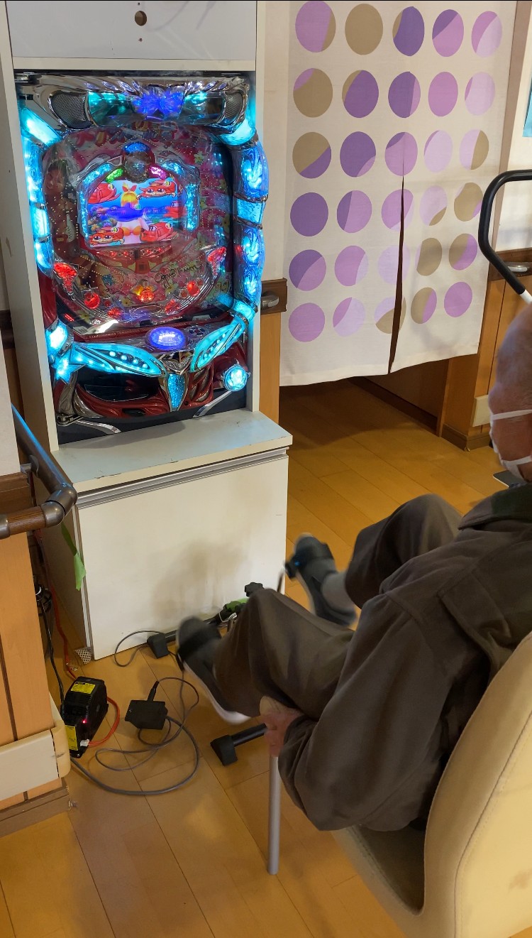 介護施設で壁際に設置されたパチンコを利用者が使用している様子