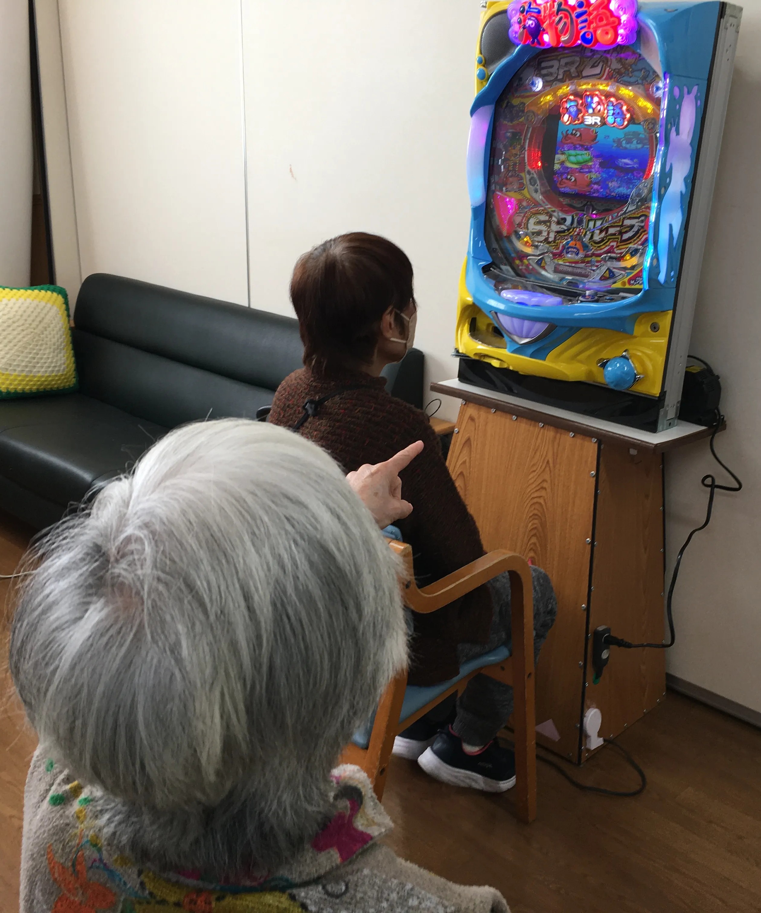 介護施設でパチンコ型の機能訓練機器を楽しむ利用者の様子